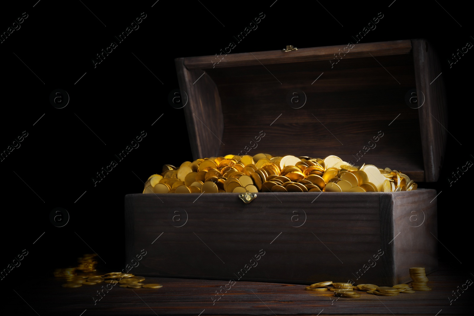 Image of Open treasure chest with gold coins on wooden table