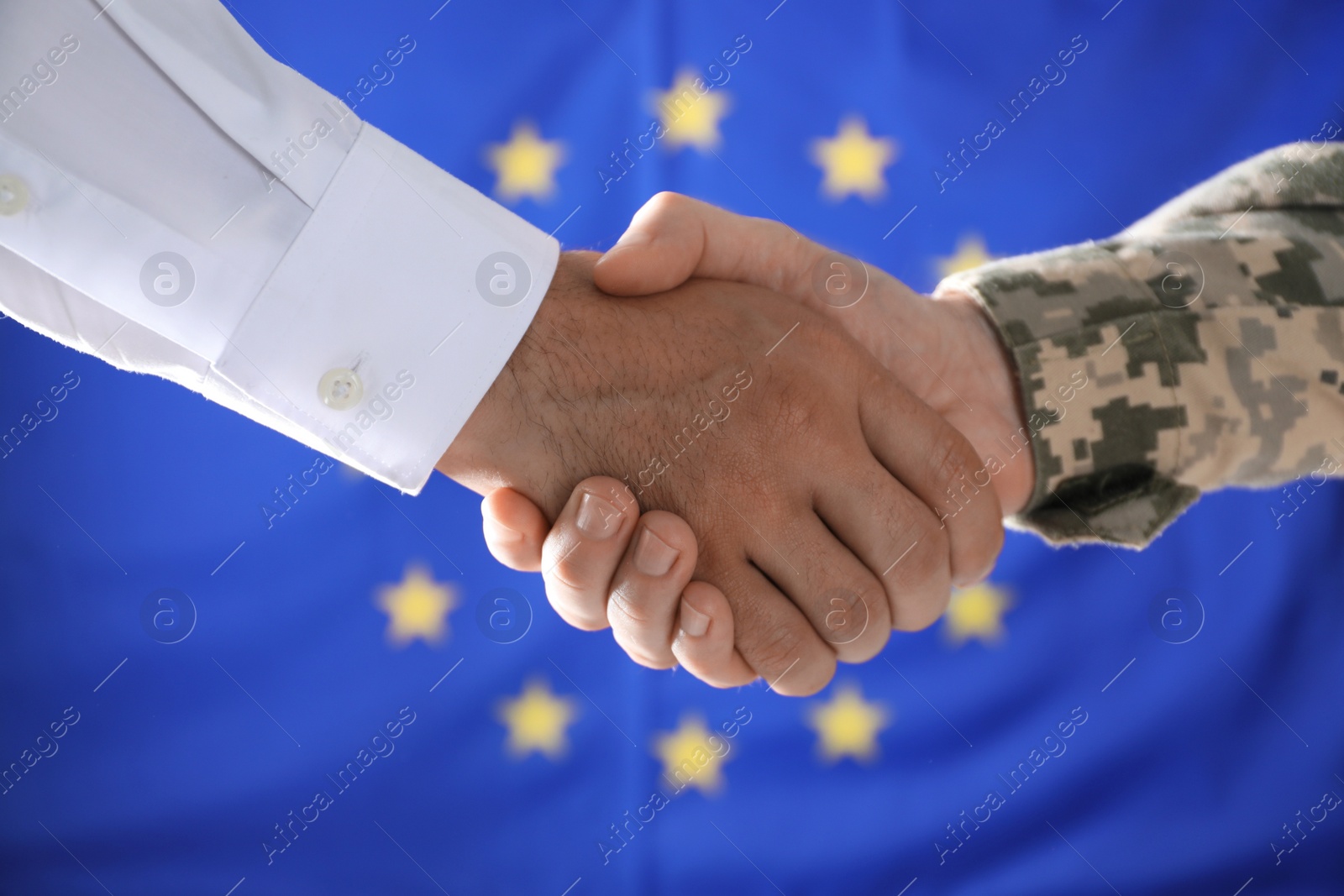 Photo of Soldier and businessman shaking hands against flag of European Union, closeup