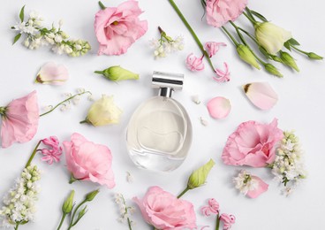 Luxury perfume and floral decor on white background, flat lay