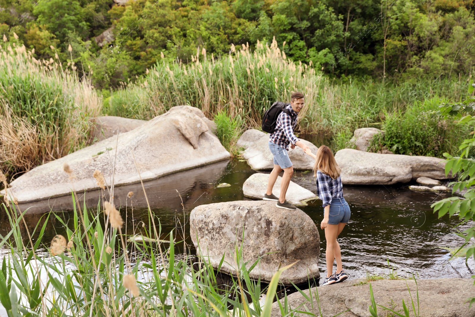 Photo of Cute young couple crossing river. Camping season