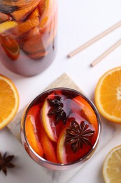 Photo of Aromatic punch drink and ingredients on white table, flat lay