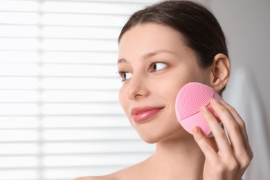 Washing face. Young woman with cleansing brush indoors, closeup. Space for text