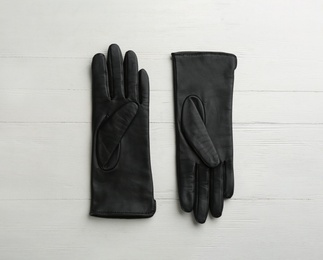 Pair of stylish leather gloves on white wooden background, flat lay