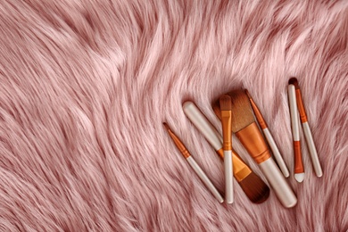Flat lay composition with makeup brushes on faux fur
