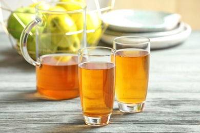 Glasses and jug of apple juice on wooden table