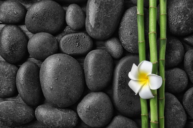 Photo of Flat lay composition with bamboo branches and spa stones as background. Space for text