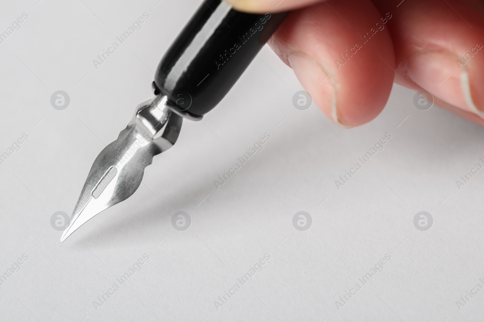 Photo of Woman with fountain pen above white paper, closeup