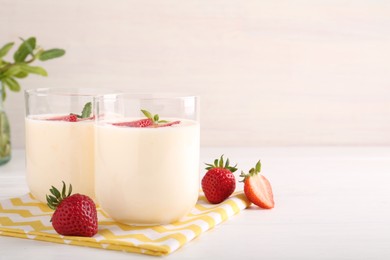 Photo of Tasty yogurt and strawberries in glasses on white wooden table. Space for text