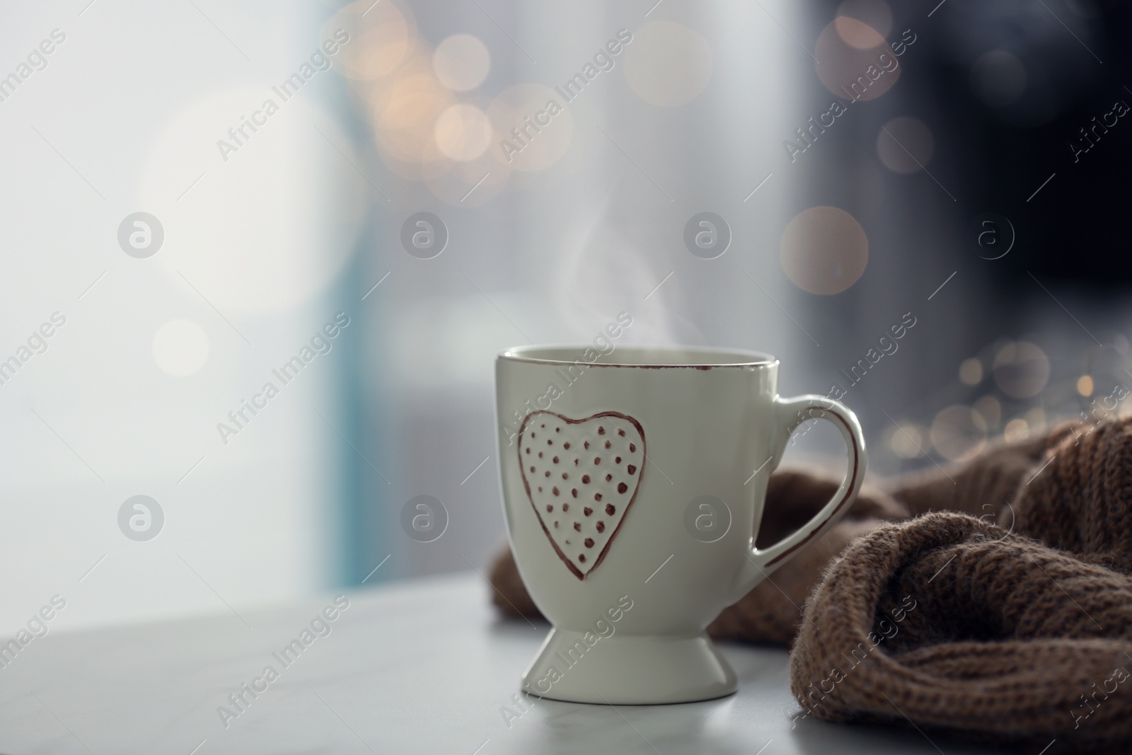 Photo of Delicious morning coffee and knitted sweater on white table indoors