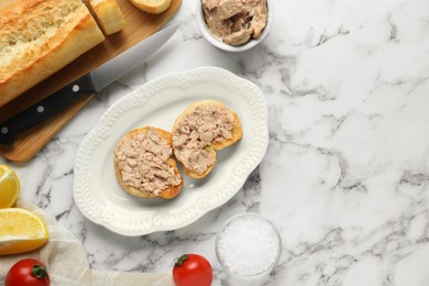 Photo of Tasty sandwiches with cod liver on white marble table, flat lay. Space for text