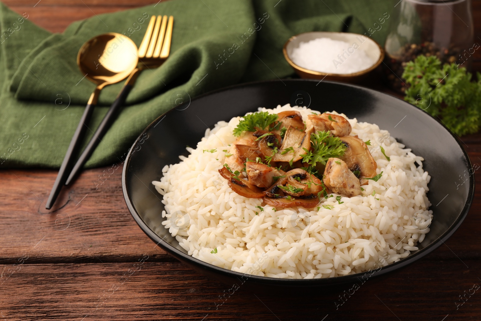 Photo of Delicious rice with mushrooms and parsley served on wooden table