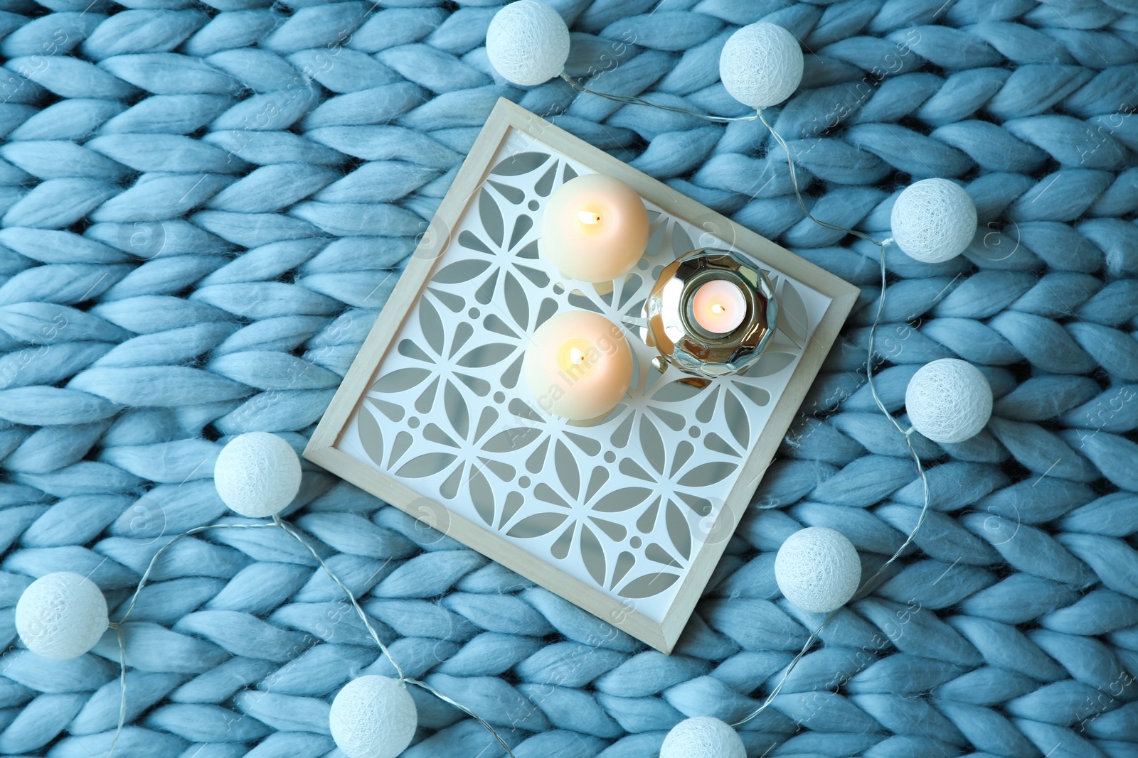 Photo of Burning candles and decor on knitted plaid, top view