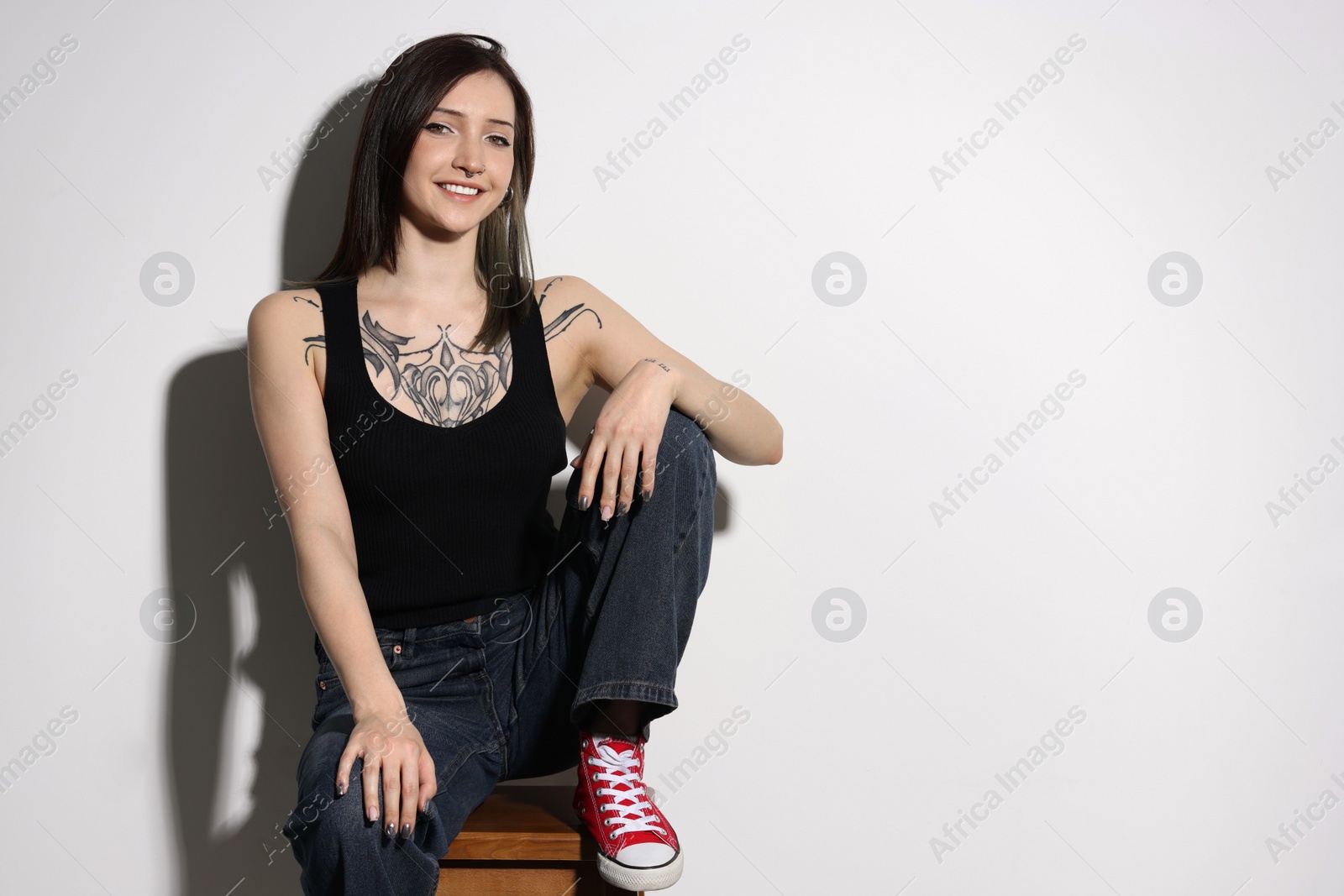 Photo of Portrait of smiling tattooed woman on light background. Space for text