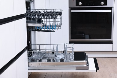 Open clean empty dishwasher in kitchen. Home appliance