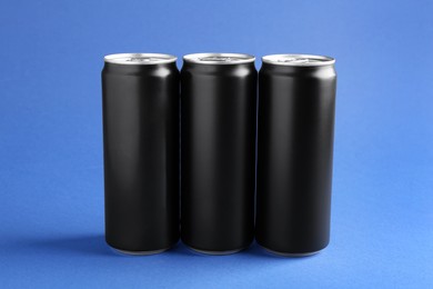 Photo of Energy drinks in black cans on blue background