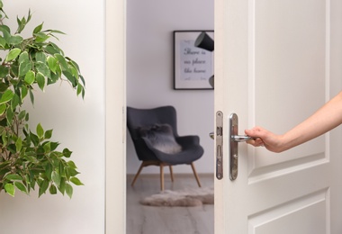 Young woman opening door to beautifully arranged room. Interior design