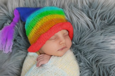 Image of National rainbow baby day. Cute child in hat with colorful pattern sleeping on furry blanket