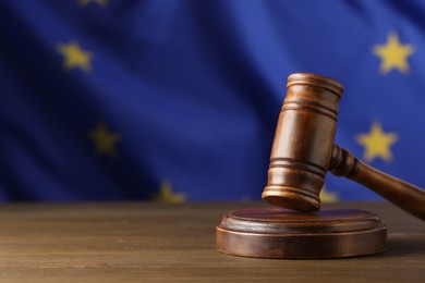 Photo of Judge's gavel on wooden table against European Union flag. Space for text