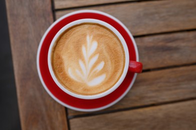 Cup of aromatic coffee on wooden table, top view