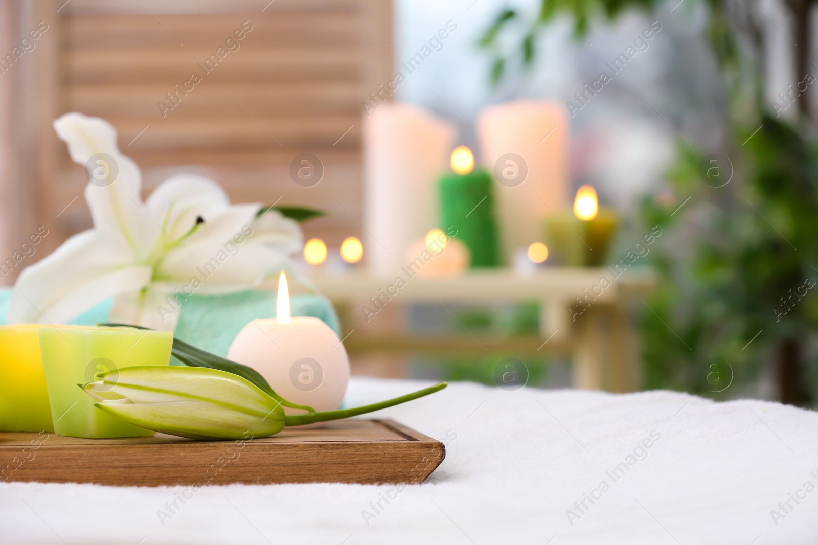 Photo of Beautiful composition with flowers and candles on massage table in salon