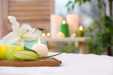 Photo of Beautiful composition with flowers and candles on massage table in salon