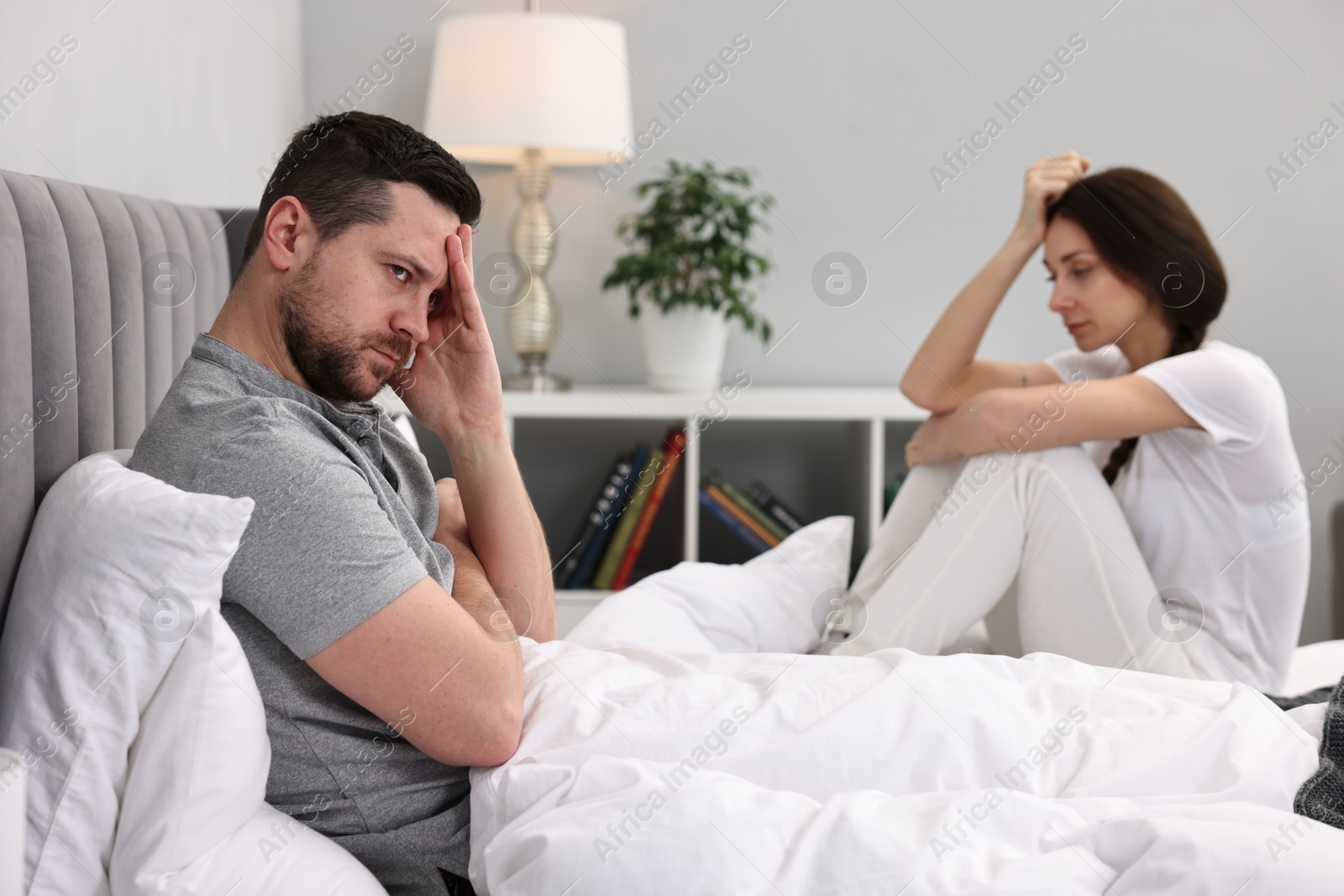 Photo of Offended couple ignoring each other after quarrel in bedroom, selective focus. Relationship problems