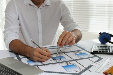 Photo of Architect working with construction drawings in office, closeup