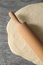 Photo of Raw dough and rolling pin on grey table, top view