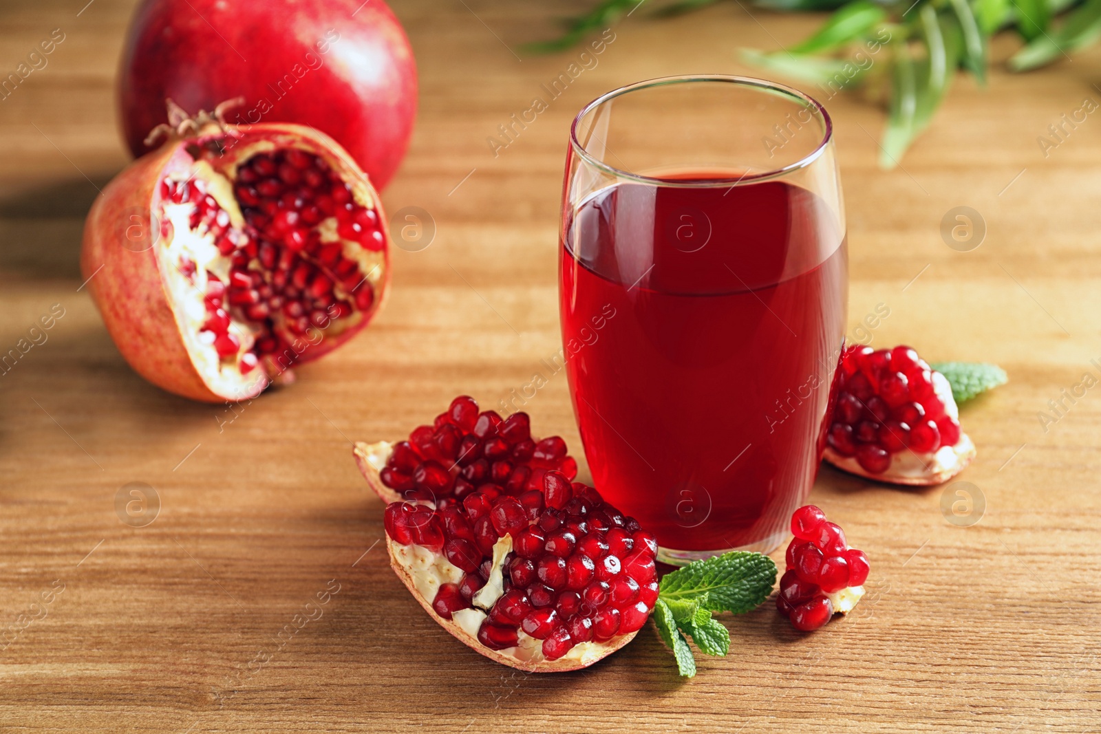 Photo of Glass of pomegranate juice and fresh fruits on wooden background