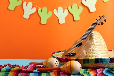 Mexican sombrero hat, maracas and ukulele on table, closeup. Space for text