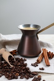 Photo of Hot turkish coffee pot, beans and spices on white wooden table