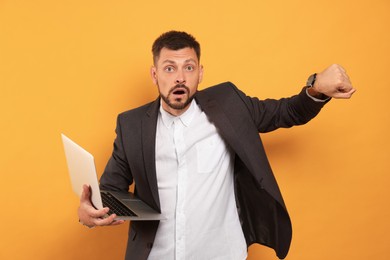 Emotional man with laptop on orange background. Being late concept