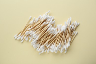 Heap of wooden cotton buds on beige background, flat lay