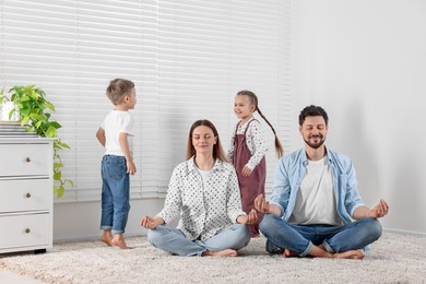 Photo of Parents meditating while children distracting them at home