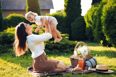 Photo of Mother and her baby daughter playing while having picnic in garden on sunny day