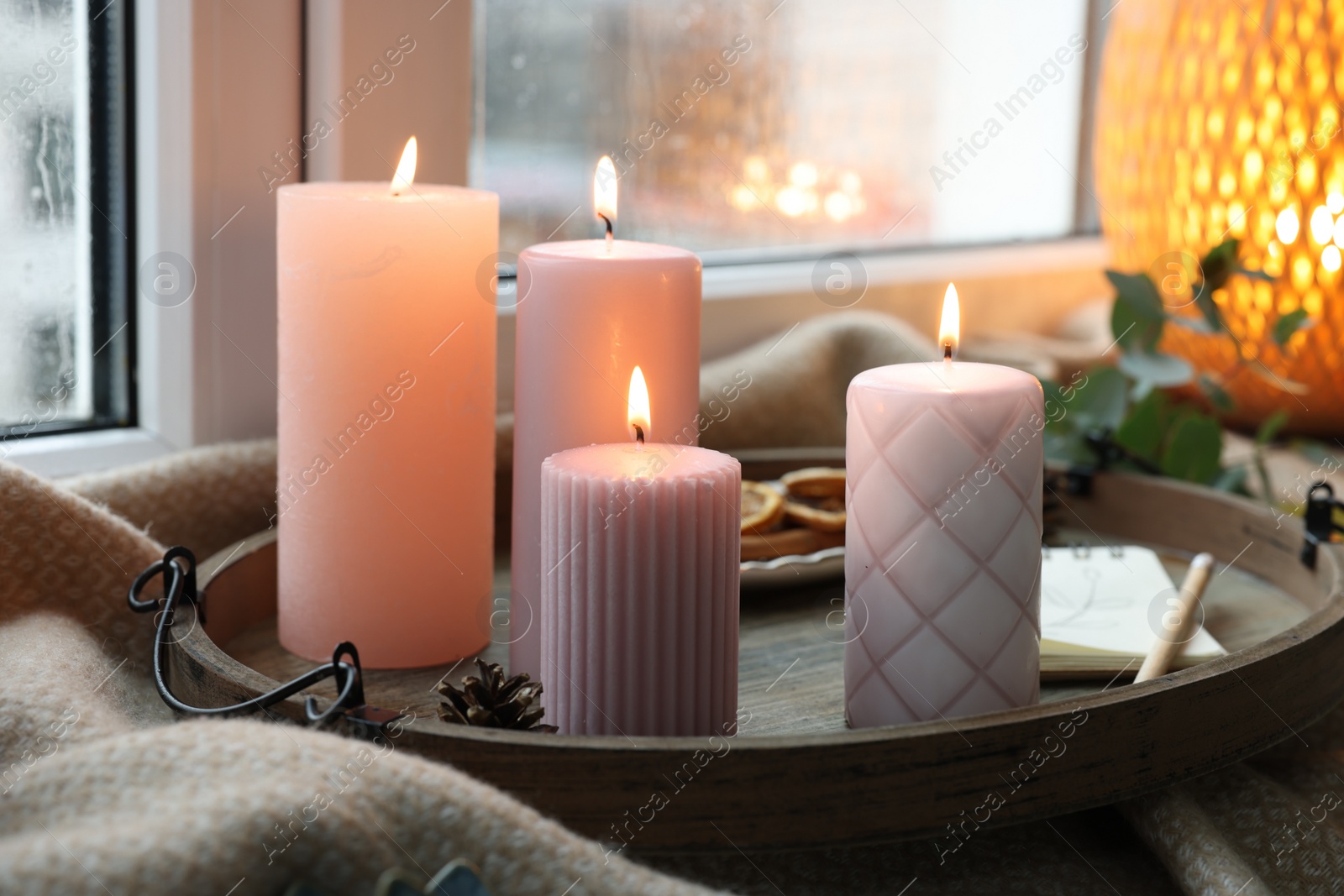 Photo of Tray with burning wax candles and decor on window sill indoors