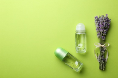 Photo of Female deodorants and lavender flowers on green background, flat lay. Space for text