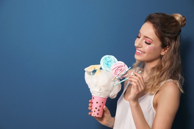 Photo of Portrait of young woman holding cotton candy dessert on blue background, space for text