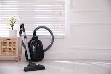 Photo of Modern vacuum cleaner near window indoors, space for text