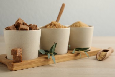 Photo of Bowls with different types of brown sugar on wooden table