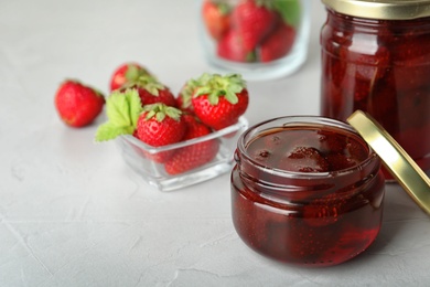Photo of Delicious pickled strawberry jam and fresh berries on light table. Space for text