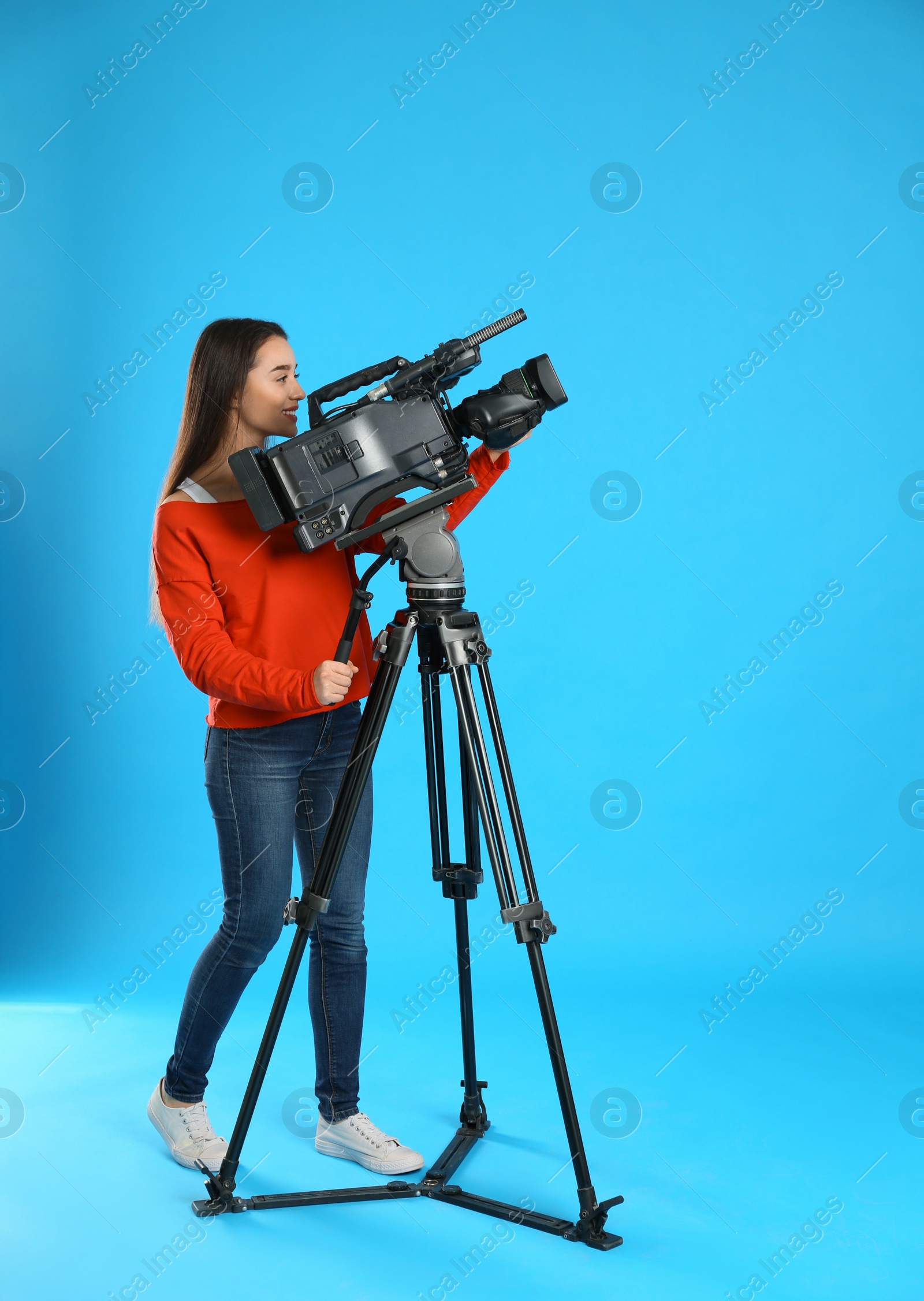Photo of Operator with professional video camera on blue background