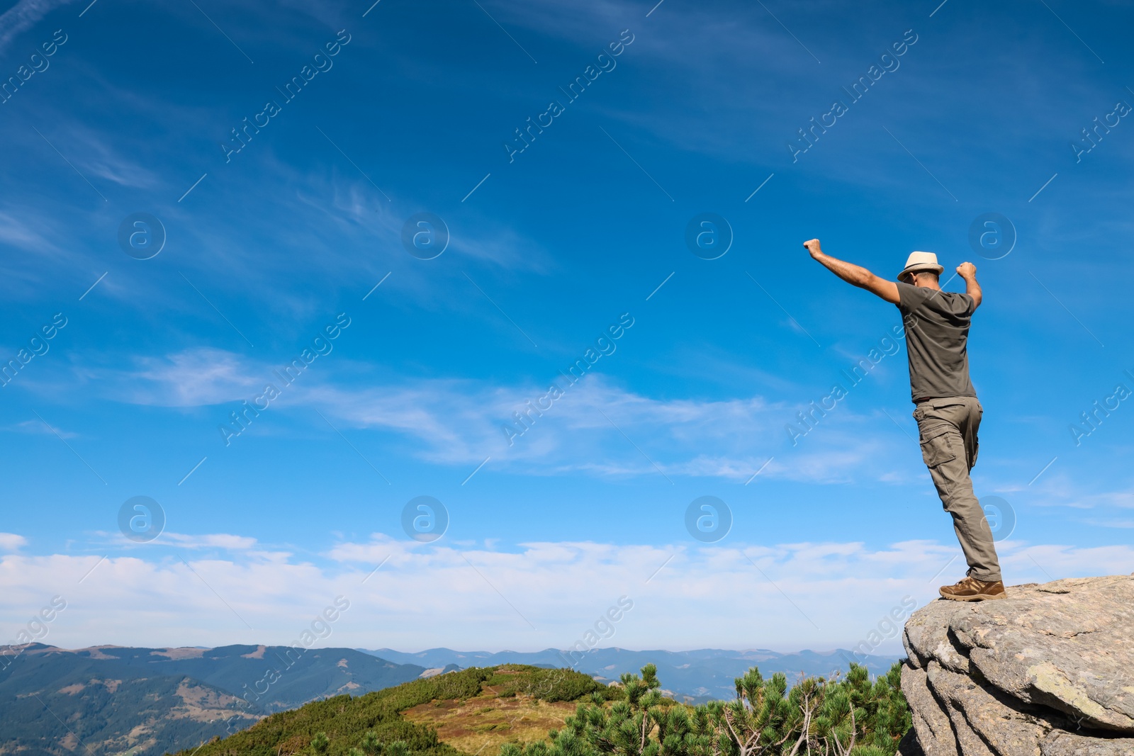 Photo of Man enjoying picturesque view on cliff in mountains. Space for text