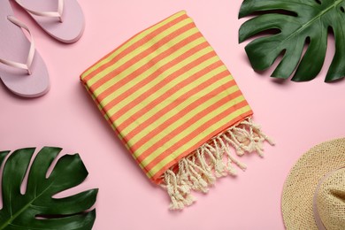 Beach towel, flip flops and hat on pink background, flat lay