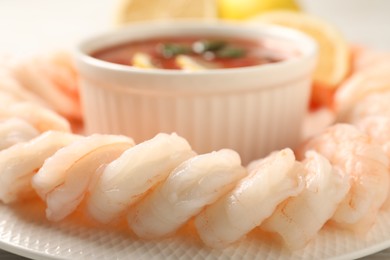 Photo of Tasty boiled shrimps with cocktail sauce and lemon on plate, closeup