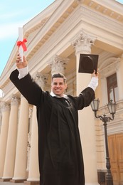 Photo of Happy student with diploma after graduation ceremony outdoors, low angle view