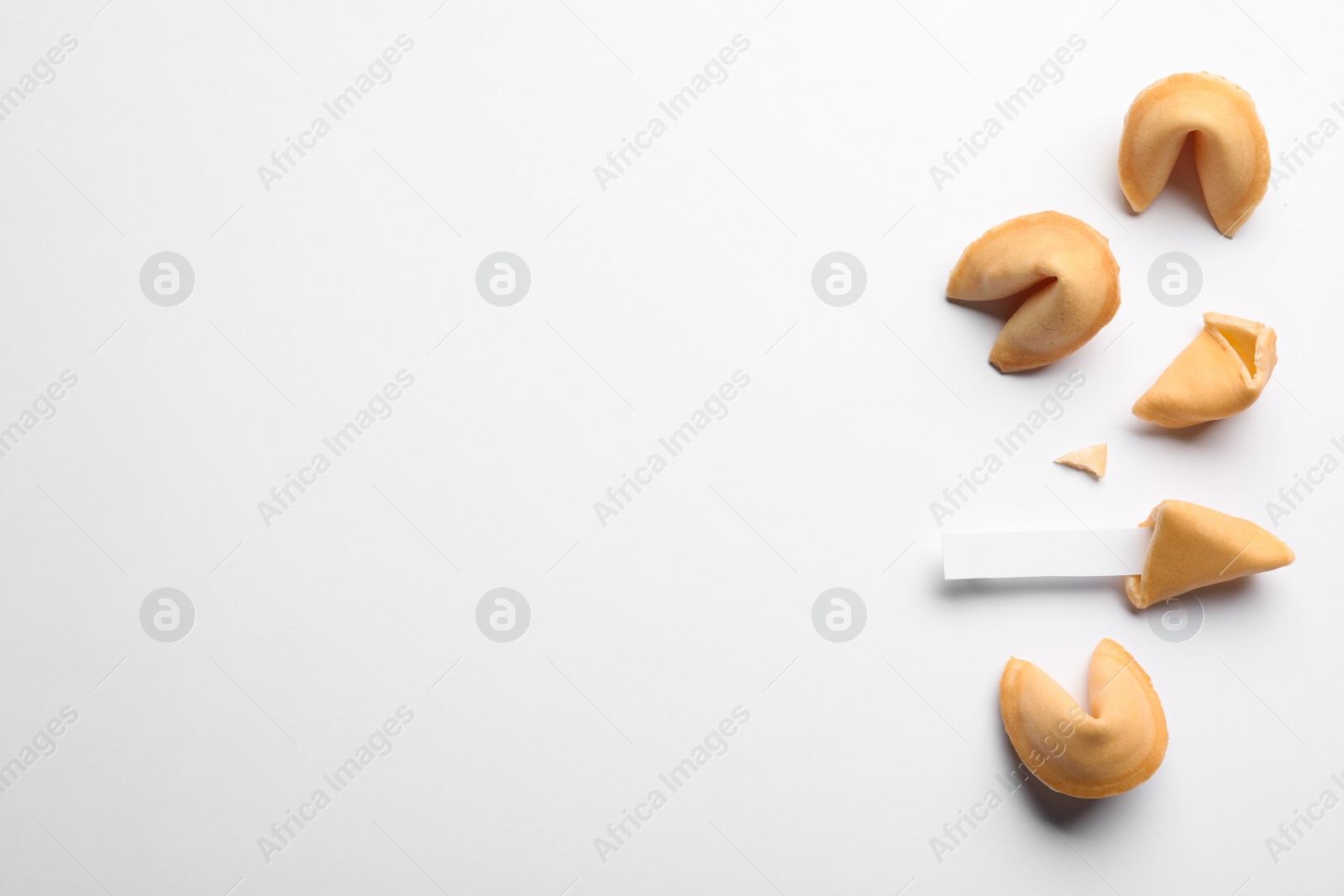 Photo of Many tasty fortune cookies with predictions on white background, flat lay. Space for text