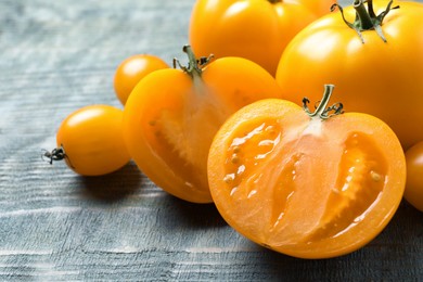 Photo of Fresh ripe yellow tomatoes on light blue wooden table, closeup