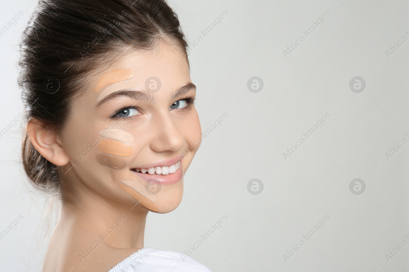 Photo of Beautiful girl on light grey background. Using concealers and foundation for face contouring