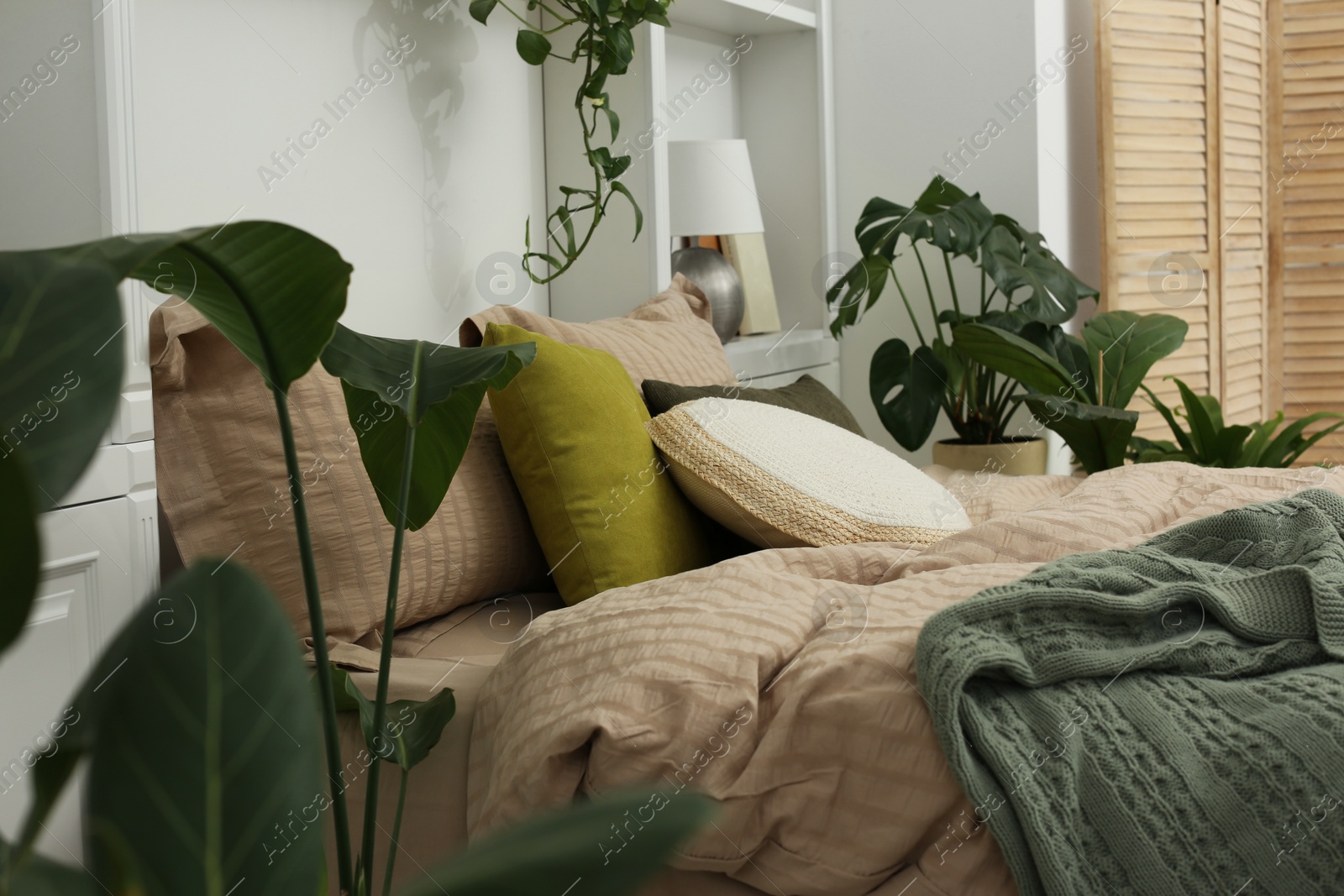 Photo of Comfortable bed and different houseplants in bedroom. Interior design